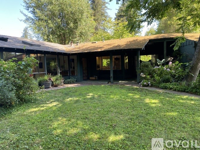 A house with a green lawn and trees in the background.