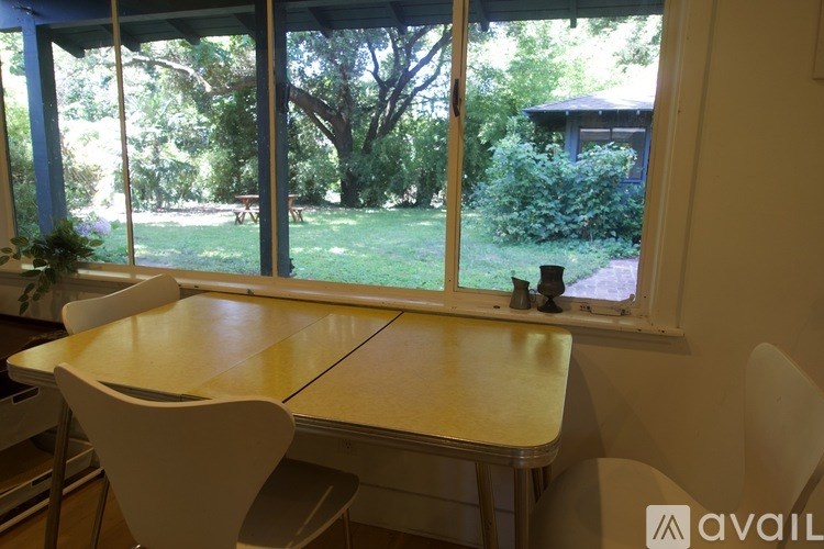 A table and chairs are set up in front of a window with a view of a garden.