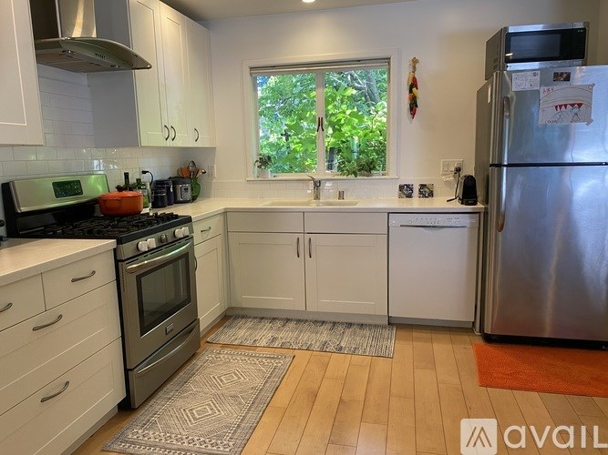 A kitchen with white cabinets and a stainless steel refrigerator.