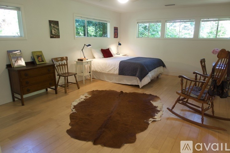 A bedroom with a bed, chair, and cowhide rug.