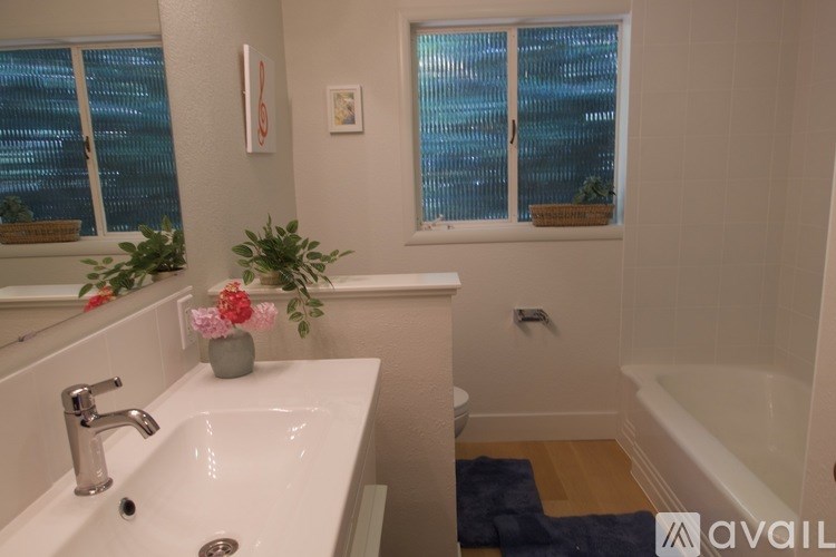 A bathroom with a white sink and a window with blinds.