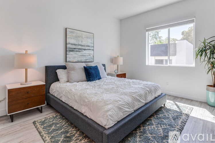 A bedroom with a large bed, two lamps, and a framed picture on the wall.