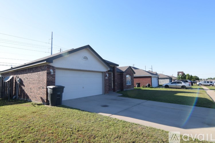 A house with a white garage door is surrounded by a grassy area and other houses.