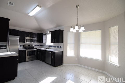 A modern kitchen with black cabinets and stainless steel appliances.