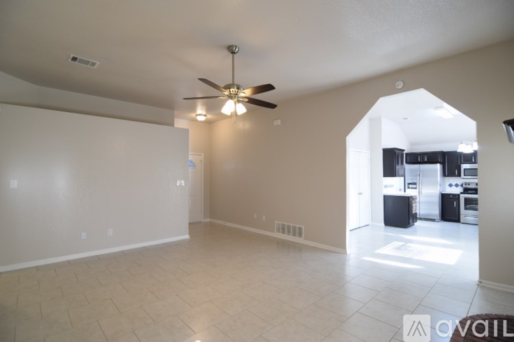 A spacious living room with a ceiling fan and tiled flooring.