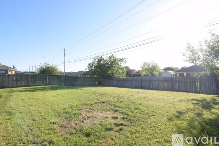 A grassy field with a wooden fence and power lines in the background.