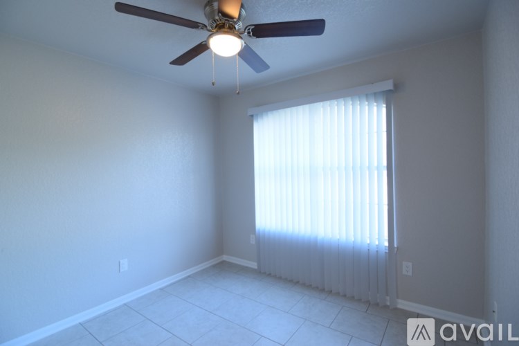 A room with a ceiling fan and a window with blinds.