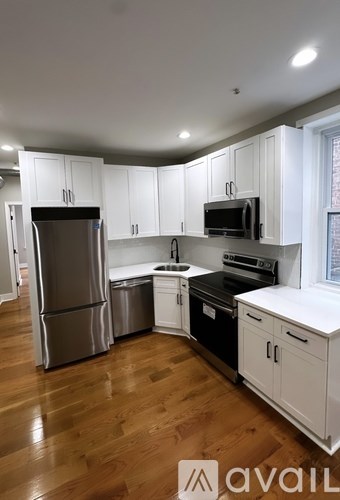 A kitchen with white cabinets and wooden floors.