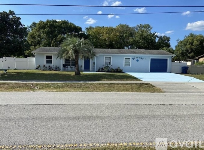 A white house with a blue garage door is situated in a residential area.
