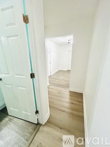 A white door with a brass handle is open to a hallway.