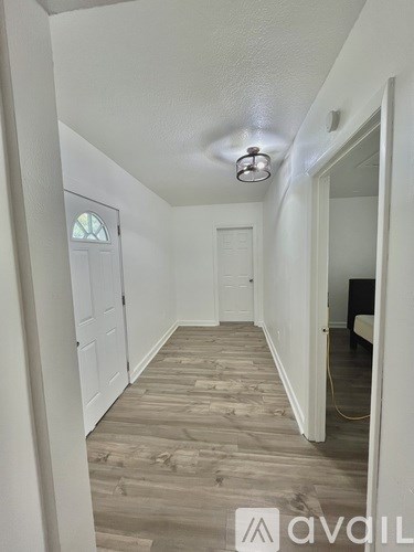 A hallway with wood flooring and white walls.
