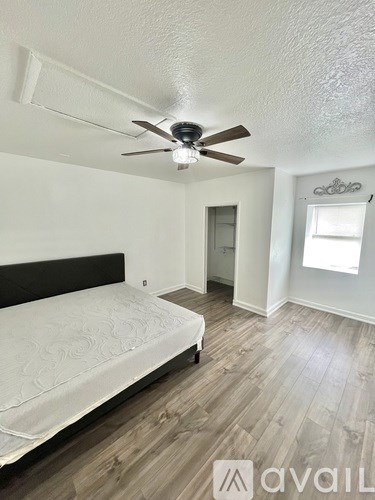 A bedroom with a bed, a ceiling fan, and a doorway leading to another room.