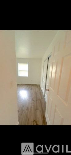 A hallway with wooden floors and white walls.