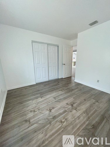 A room with wooden flooring and a white door.