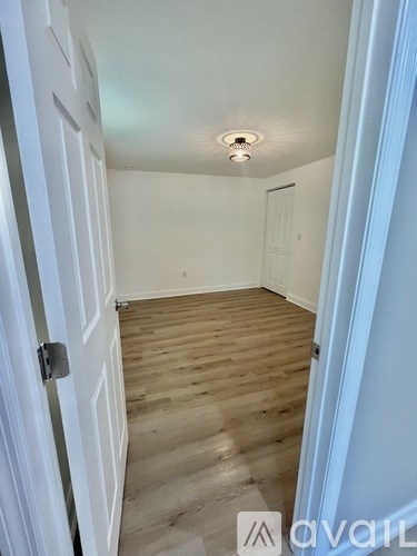 A hallway with a wooden floor and white walls.