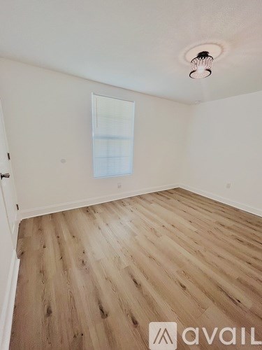 A room with wooden flooring and a window.
