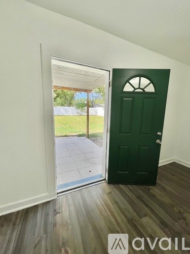 A room with a green door and wooden flooring.