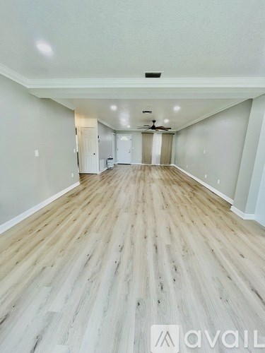 A spacious room with wooden flooring and white walls.
