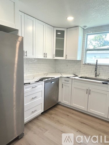 A kitchen with white cabinets and a stainless steel refrigerator.