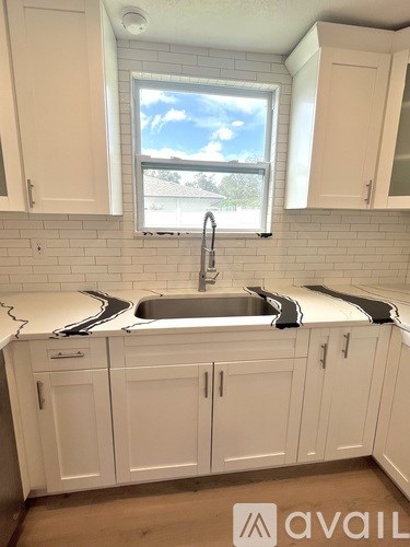 A kitchen with white cabinets and a window.