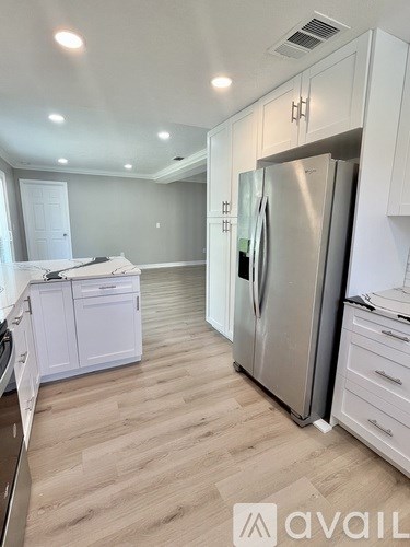 A kitchen with white cabinets and a stainless steel refrigerator.