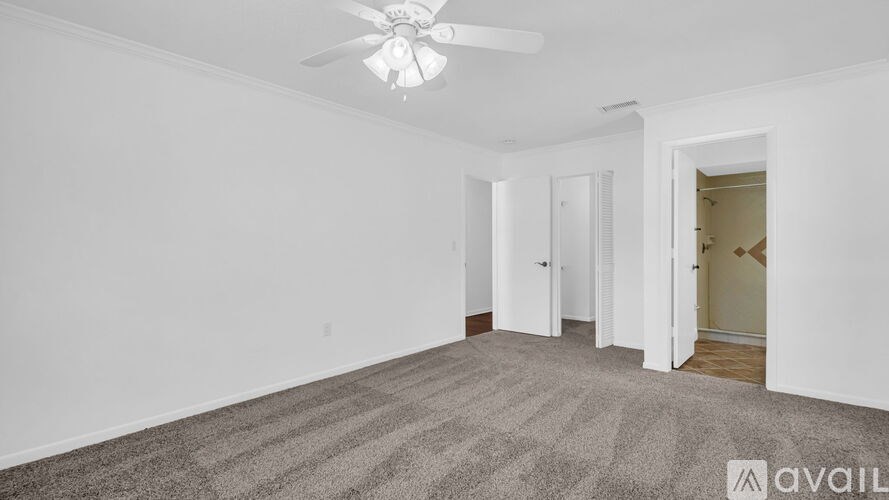 A room with a carpeted floor and a ceiling fan.