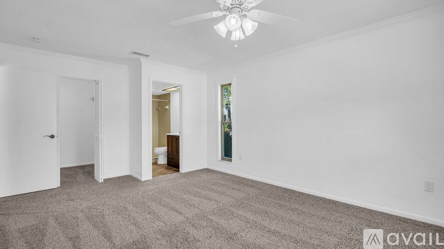 A spacious room with a carpeted floor and a ceiling fan.