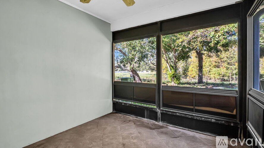 A room with a large window overlooking a tree-filled landscape.