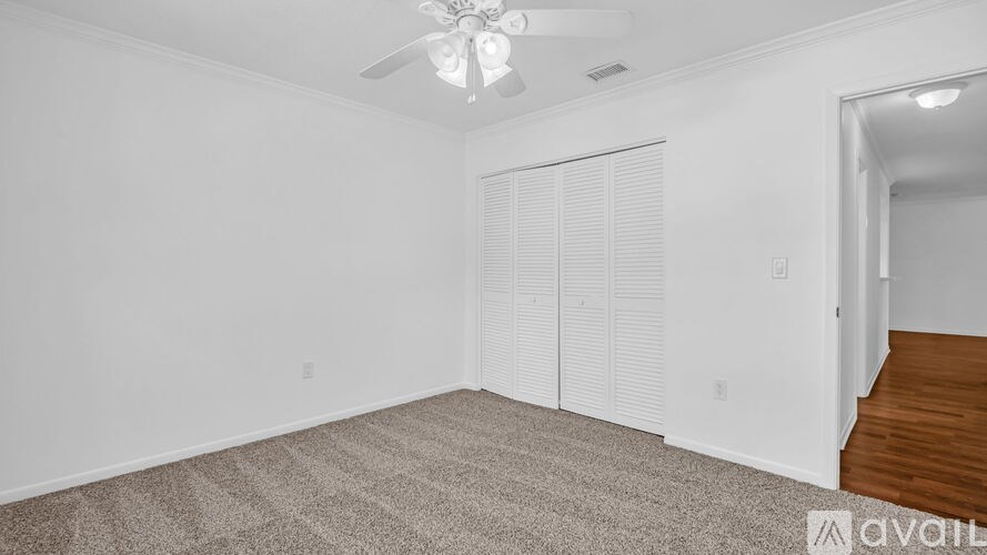 A room with a carpeted floor, a ceiling fan, and a door with a window covered by blinds.