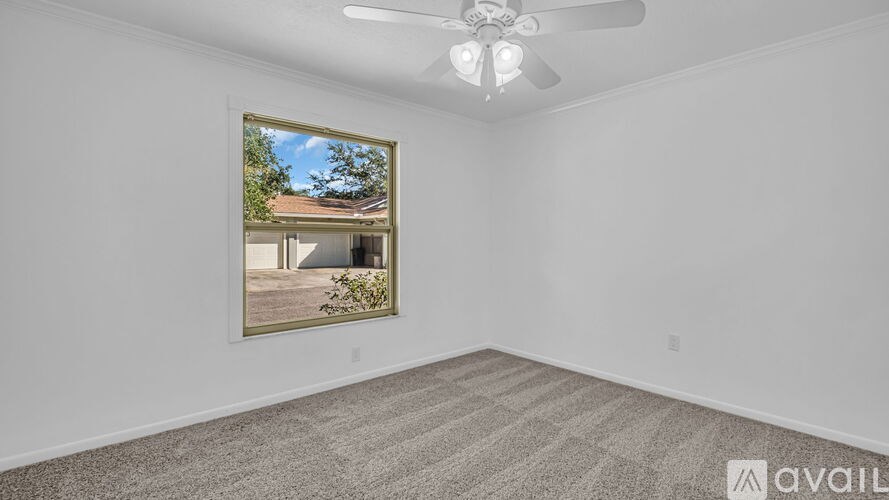 A room with a ceiling fan and a picture frame on the wall.