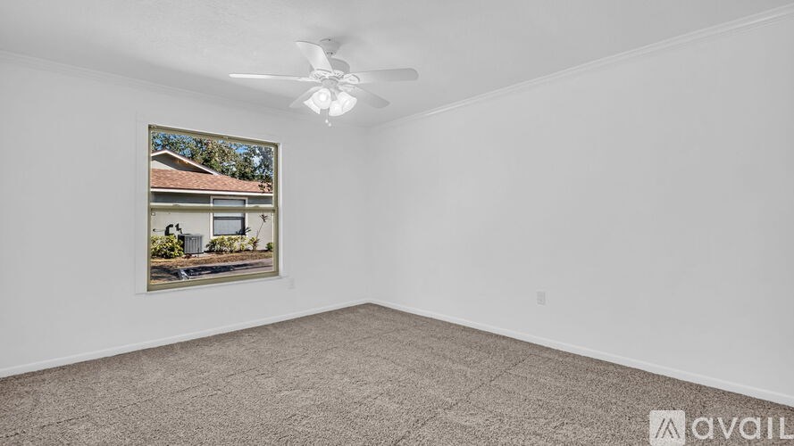 A room with a carpeted floor and a ceiling fan.