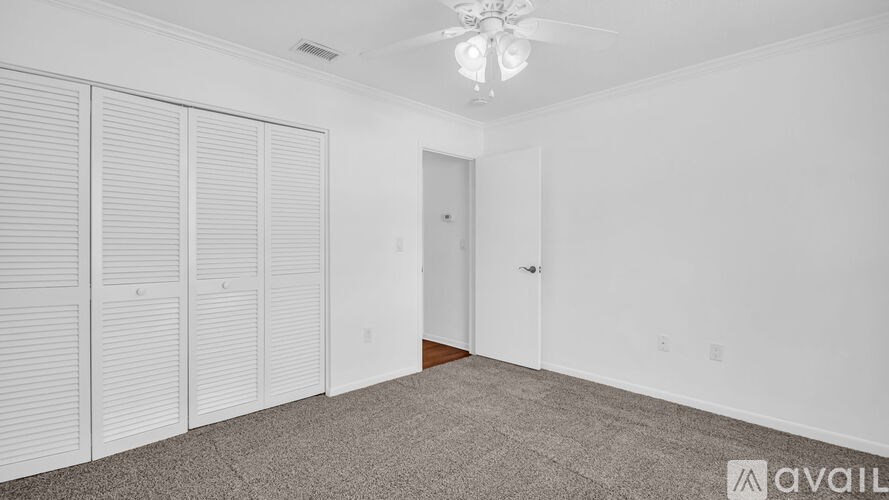 A room with a ceiling fan and a carpeted floor.