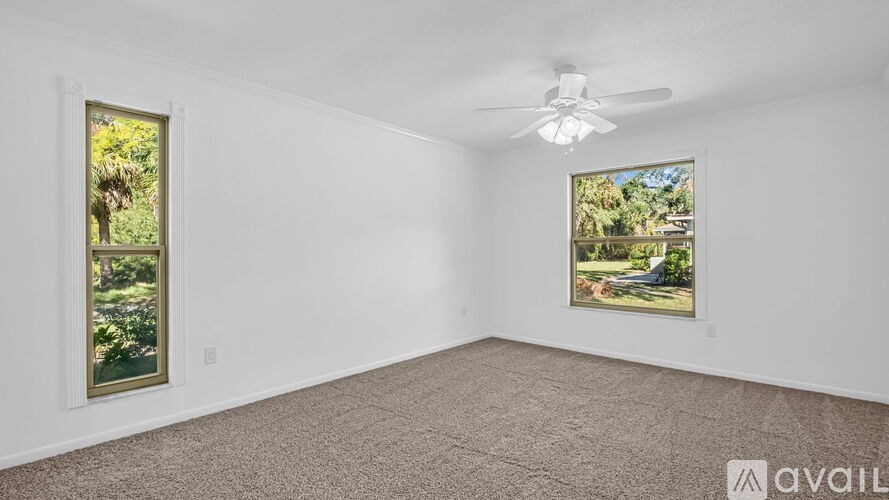 A room with a carpet floor, a ceiling fan, and two framed pictures on the wall.