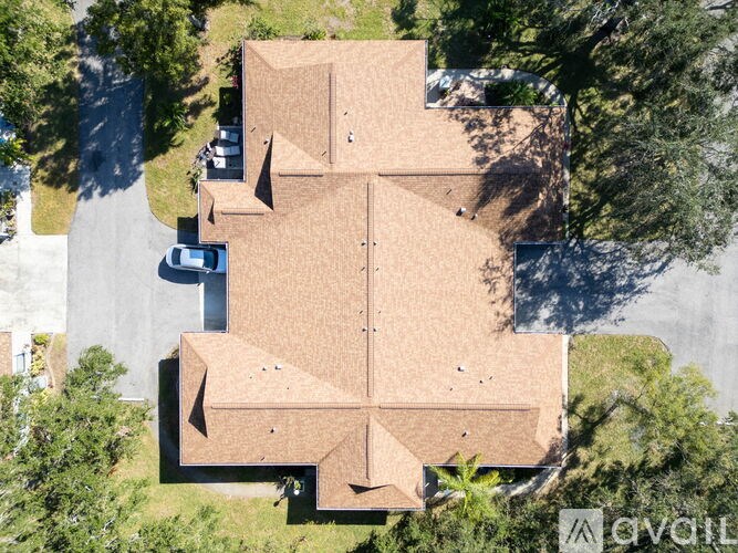 A bird's eye view of a house with a brown roof and a driveway.