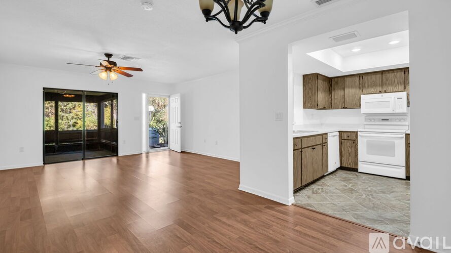 A spacious room with a ceiling fan and a kitchen area in the background.