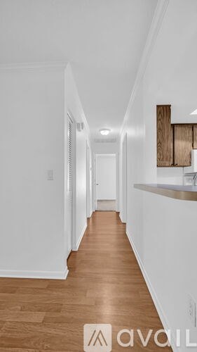A long hallway with wood floors and white walls.