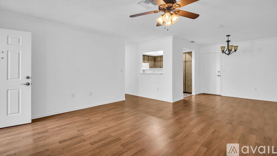 A spacious room with a ceiling fan and hardwood flooring.