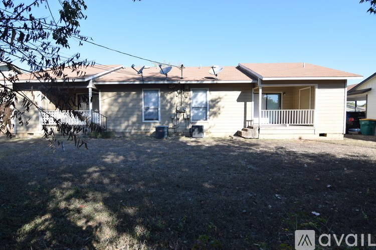 A house with a brown roof and a white fence is available for rent.