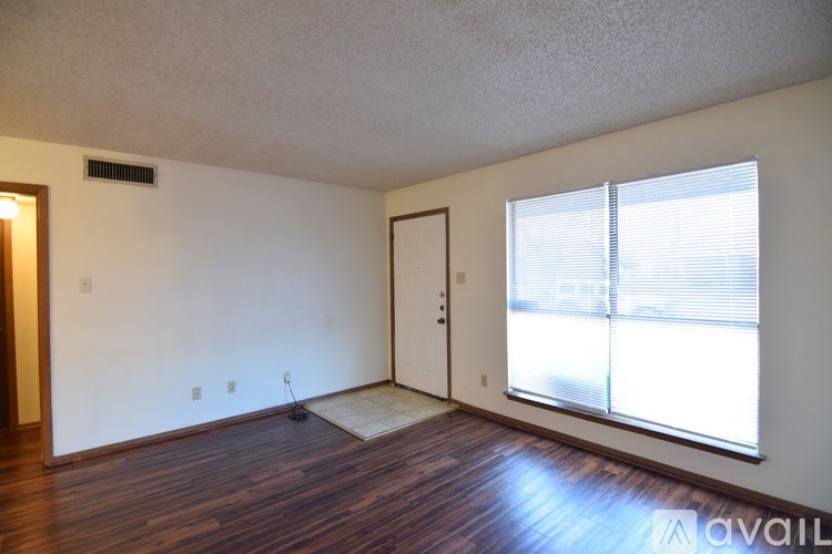 A room with a wooden floor and a window with blinds.