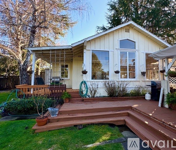 A house with a deck and a tree in front.