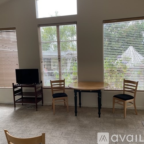A room with a table, chairs and a television.
