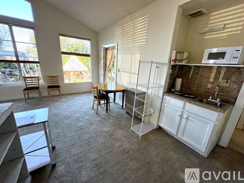 A kitchen area with a sink, a microwave, and a dining table with chairs.