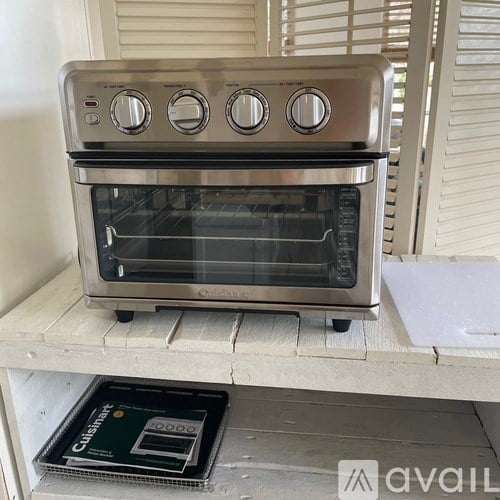 A stainless steel oven with four knobs is on a shelf.
