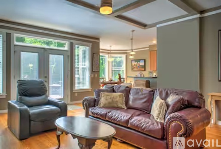A living room with a brown leather couch and a grey armchair.