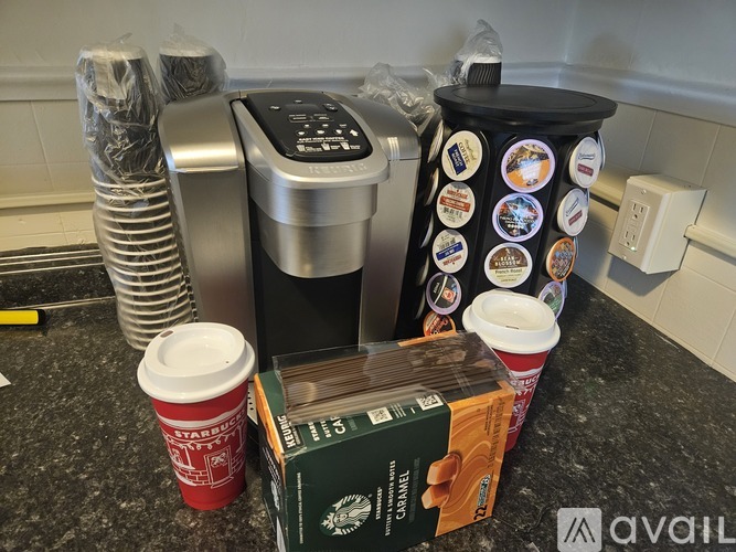 A kitchen counter with a Starbucks cup, a box of Starbucks coffee, and a container of cookies.