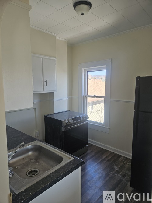 A kitchen with black appliances and a window.