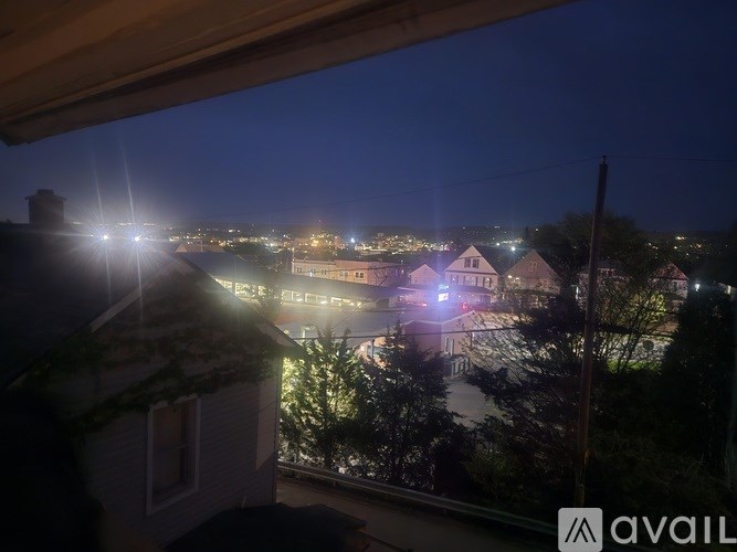 A view from a window at night showing a cityscape with buildings and lights.