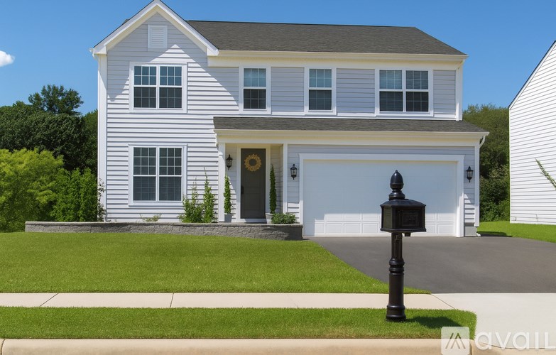 A two-story house with a garage and a mailbox in front.
