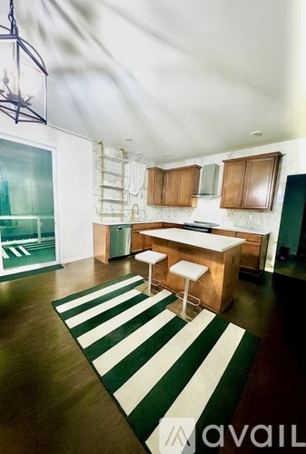 A kitchen with a bar stool and a striped rug.