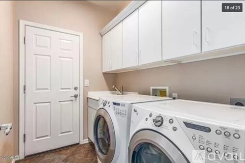 A white door is next to a washer and dryer in a laundry room.